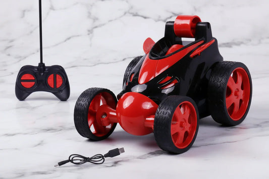 Black and red remote control stunt car toy with controller and USB charging cable on marble surface