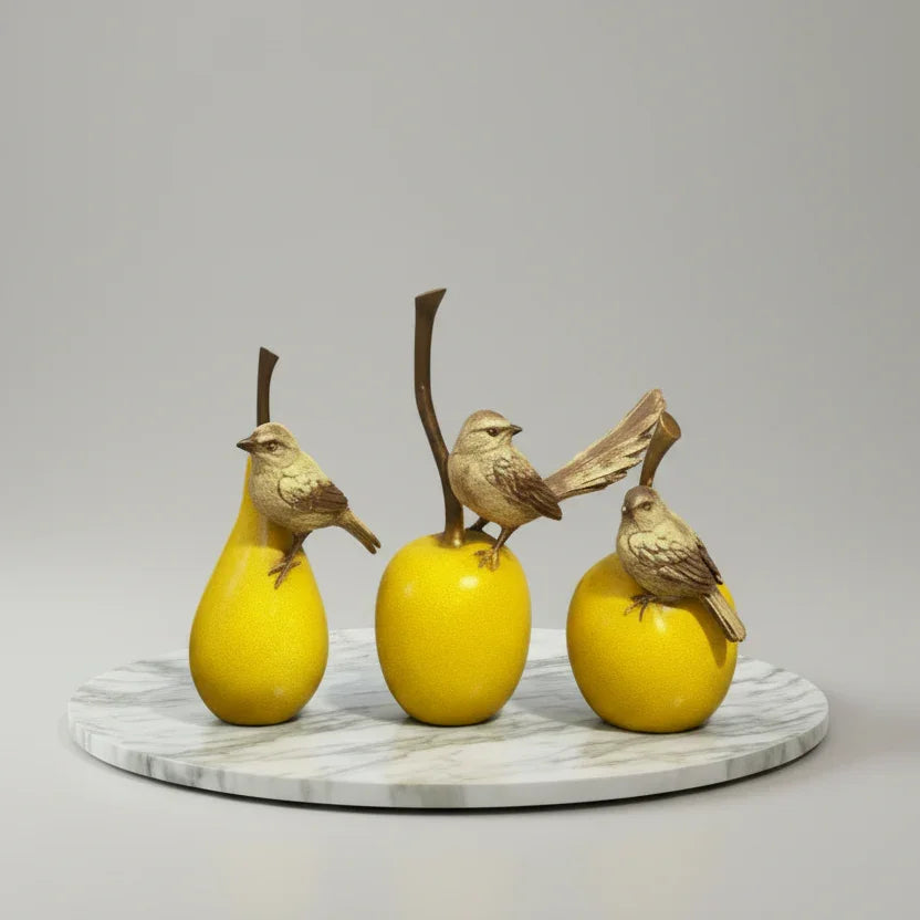 Decorative yellow fruit figurines with small birds on a marble base, tabletop decor
