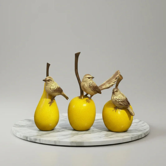 Decorative yellow fruit figurines with small birds on a marble base, tabletop decor