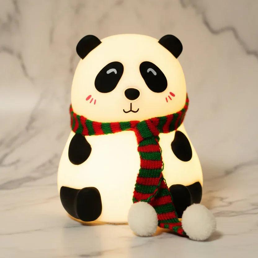 Silicone panda night light toy with a green and red striped scarf on marble background