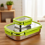 Stainless steel lunch boxes with green lids on a wooden table, kitchen background